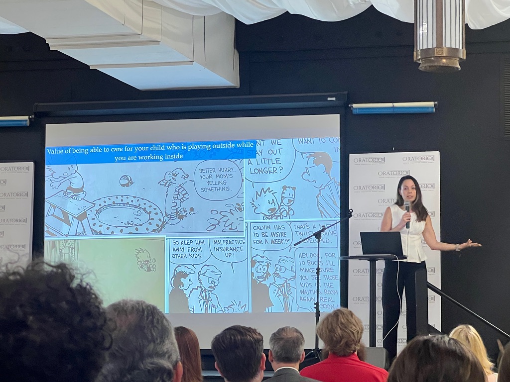 A presenter speaking to an audience with a projected slide about children and outdoor play.