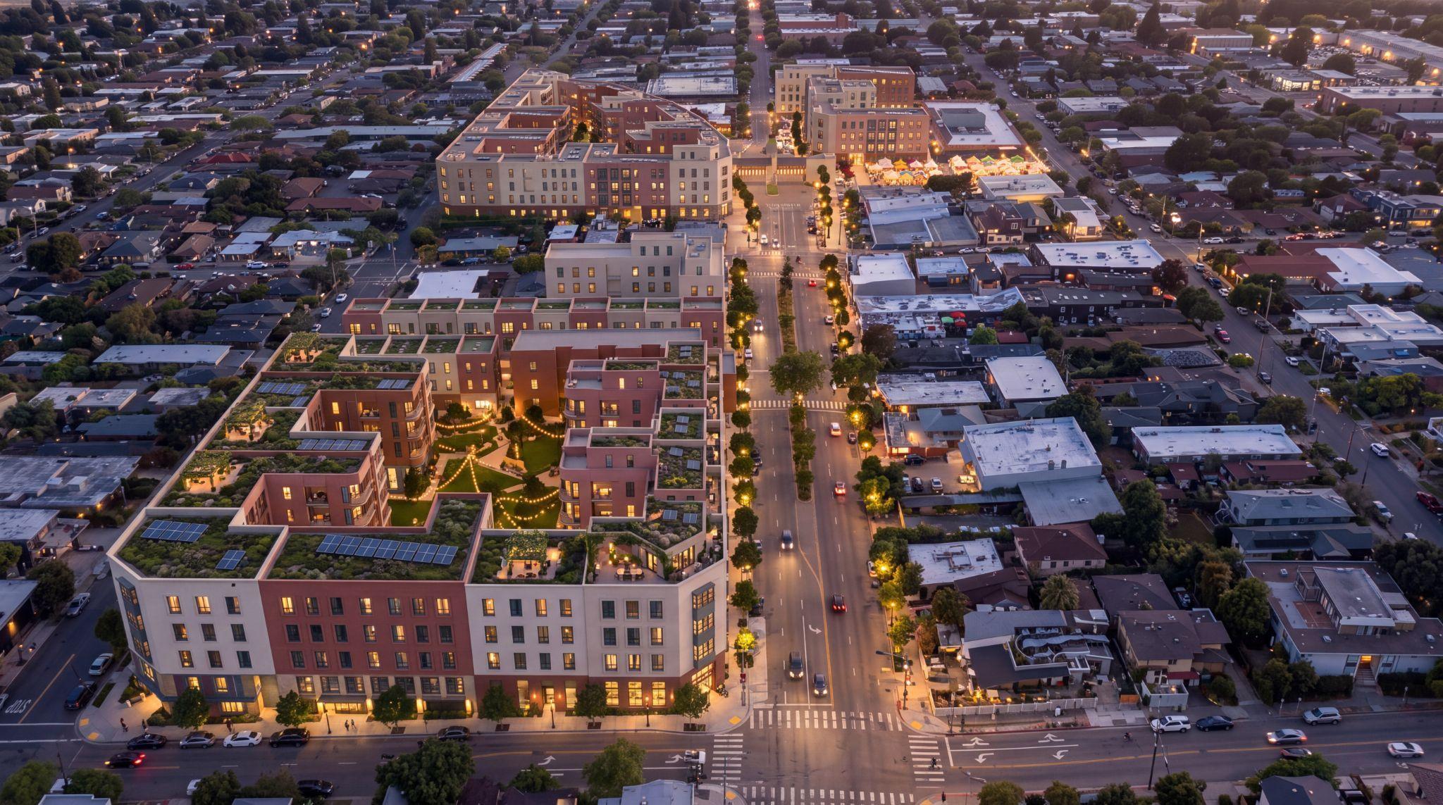 Illustrative evening aerial of the courtyard proposal, with lit homes, garden paths and the market plaza.